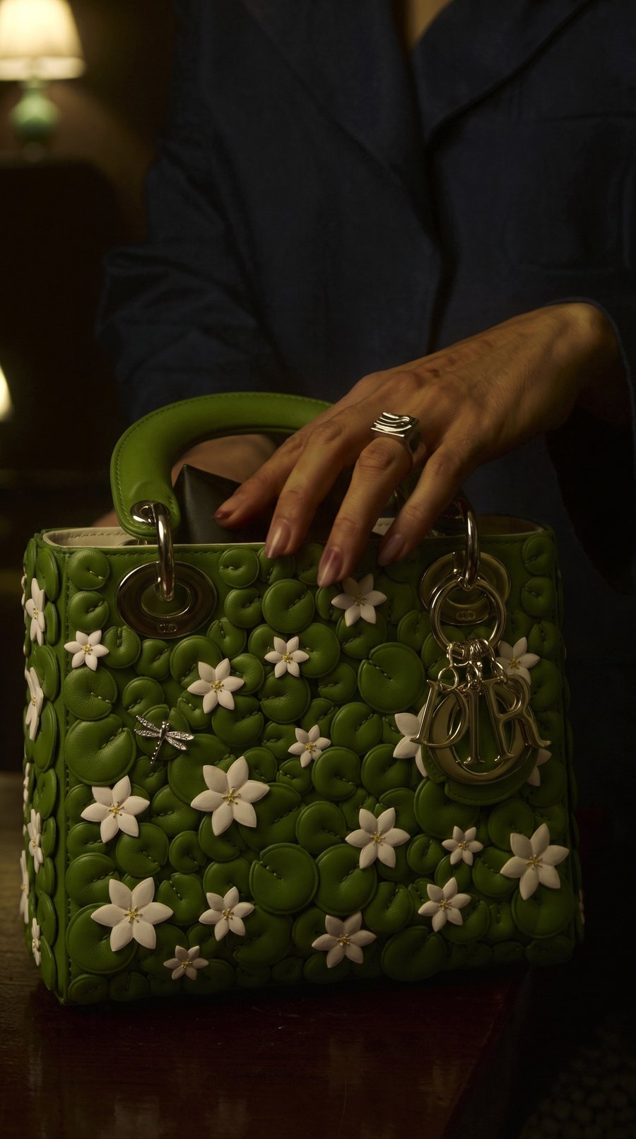 After Product Blend: the green bag sits in the dim, warm room light, its silver hardware dark and warm